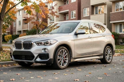 BMW X1 F48 d'occasion garée dans une rue résidentielle en automne, vue trois-quarts avant sur carrosserie argentée légèrement usée