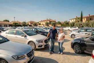 Vue large d'un lot de voitures d'occasion dans l'Hérault avec un vendeur accompagnant des clients